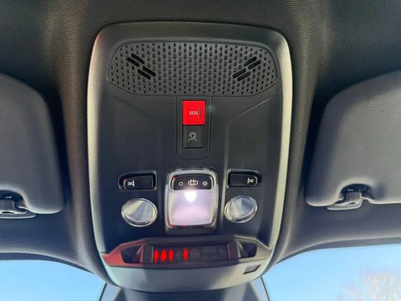 Plafonnier intérieur du Peugeot 2008 Hybrid 2025 avec boutons SOS rouges et éclairage central blanc, vue en contre-plongée.