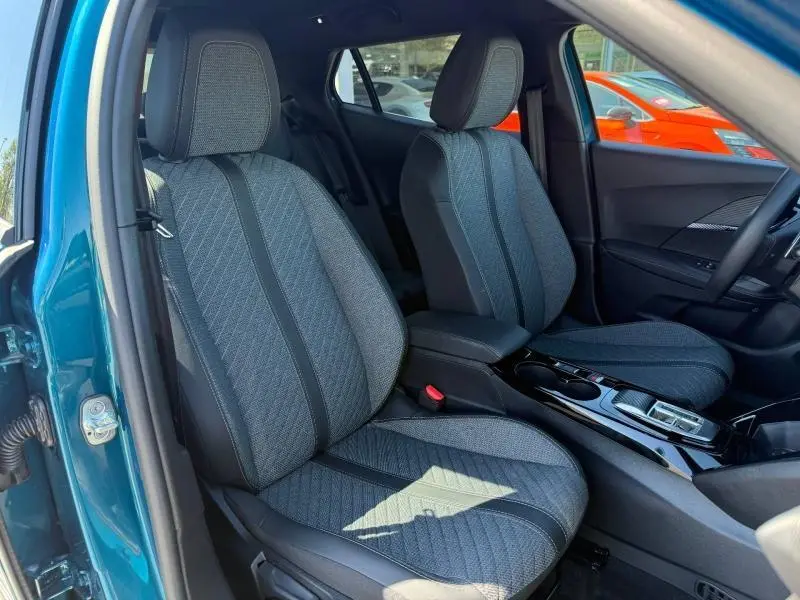 Vue intérieure des sièges avant en tissu gris avec surpiqûres, dans une Peugeot 2008 bleu Obsession 2025, porte ouverte côté gauche.