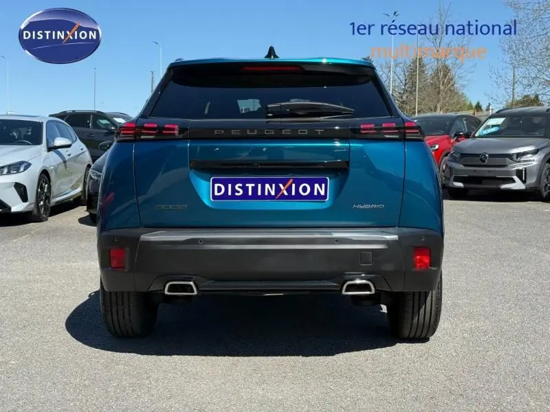 Vue arrière d'un Peugeot 2008 hybride bleu Obsession 2025 avec feux arrière à LED et double sortie d'échappement.
