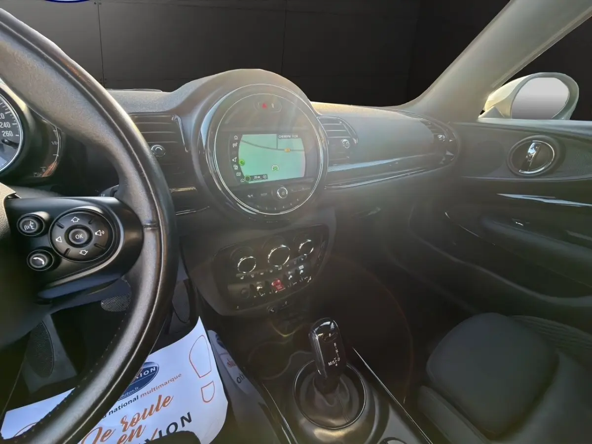Vue intérieure côté conducteur du tableau de bord noir du MINI Clubman Cooper Exquisite avec écran tactile central allumé.