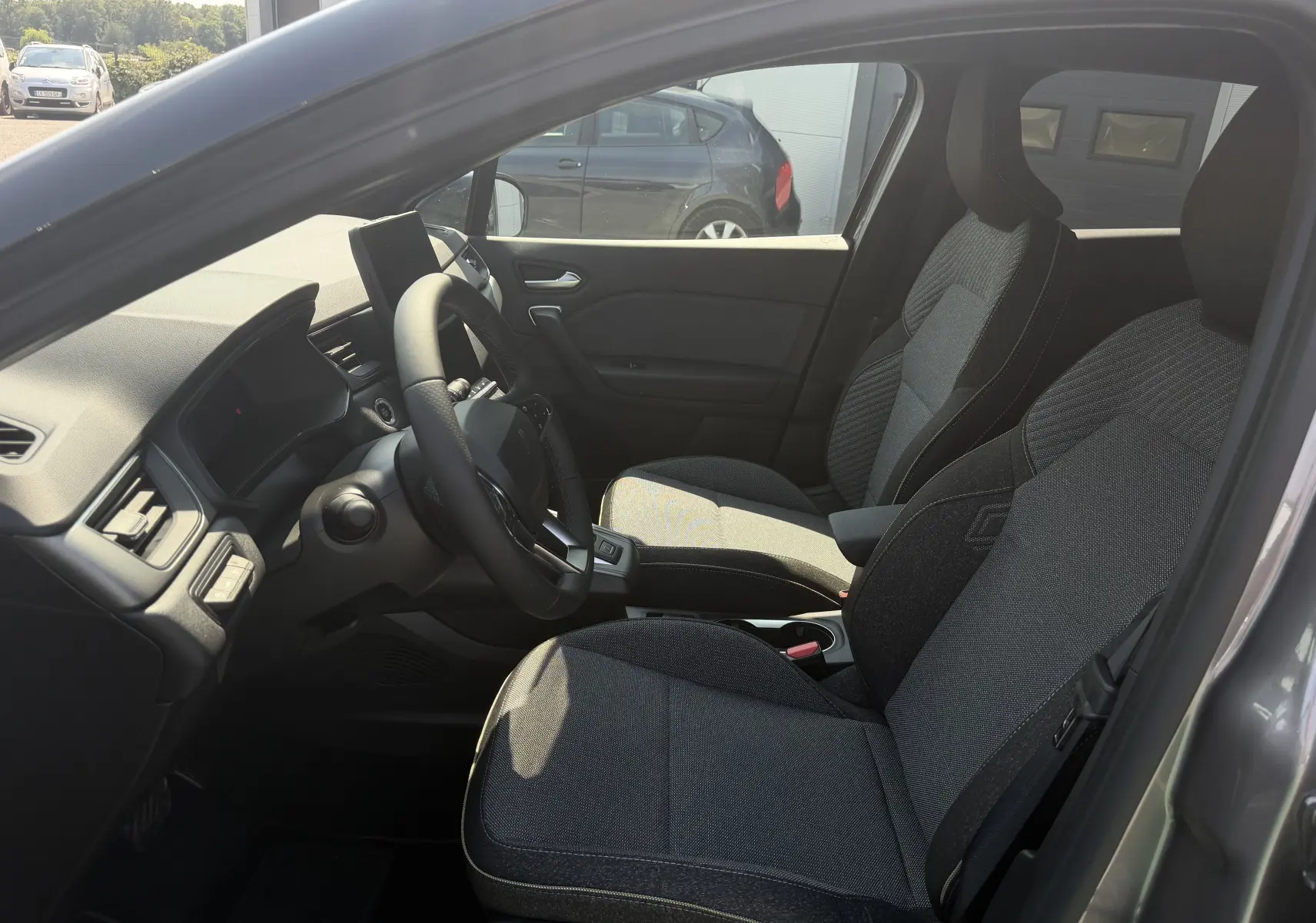 Vue intérieure côté conducteur du Renault Captur gris Cassiopée, avec sièges Techno et volant textile grainé.