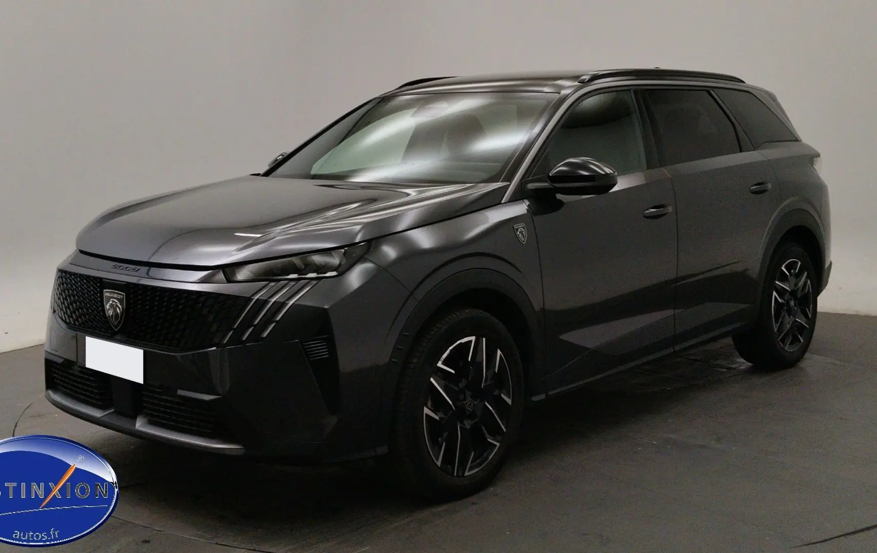Peugeot 5008 III Hybrid gris titane en 3/4 avant droit, mettant en valeur sa calandre distinctive et ses jantes bi-ton.