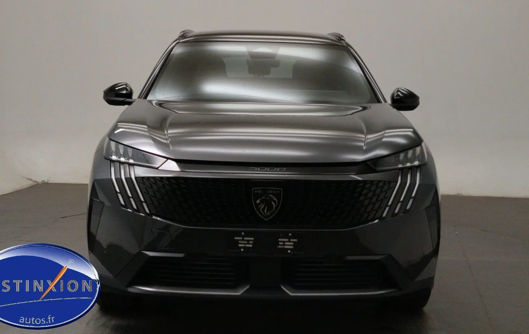 Vue frontale du Peugeot 5008 III Hybrid 145 gris titane avec calandre noire et signature lumineuse verticale LED.