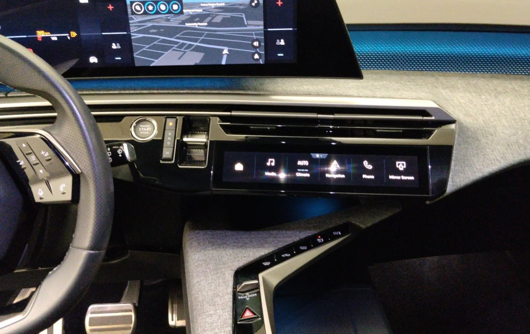 Vue intérieure du tableau de bord du Peugeot 5008 III Hybrid gris titane, avec écran tactile central et volant partiel visible.