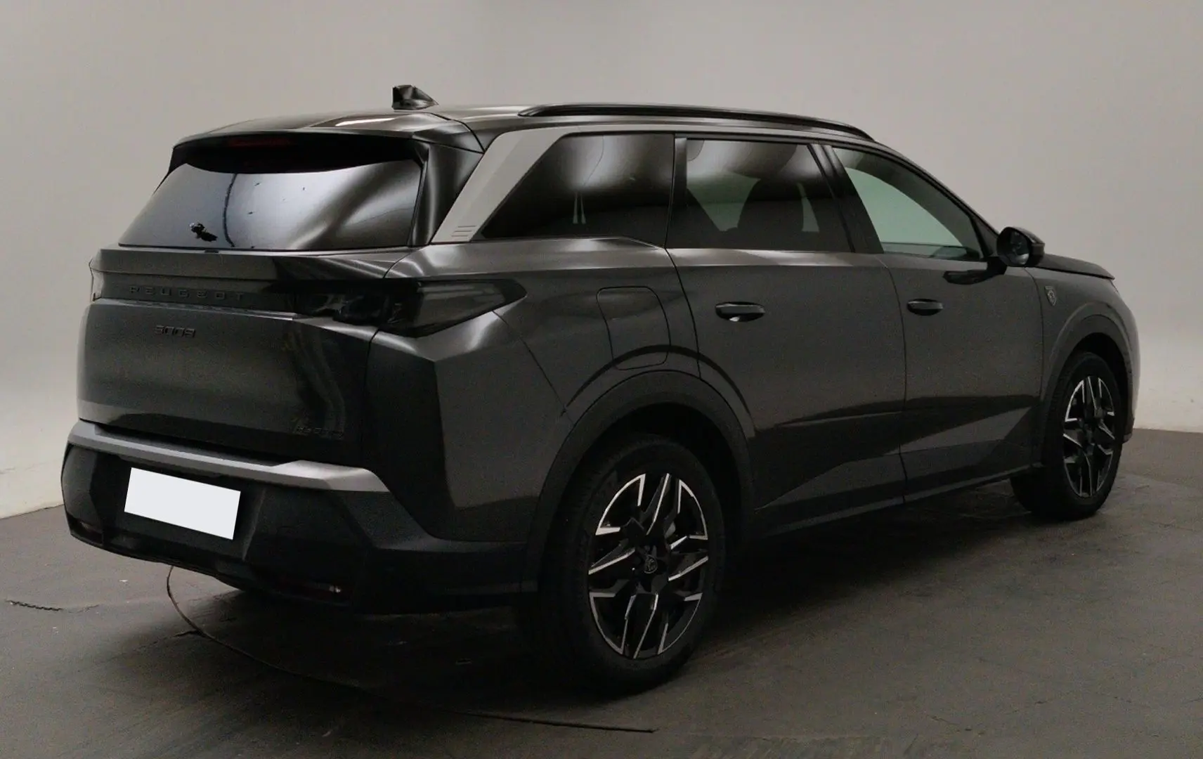 Peugeot 5008 III Hybrid gris titane en 3/4 arrière droit, avec jantes alliage noires et toit noir brillant.