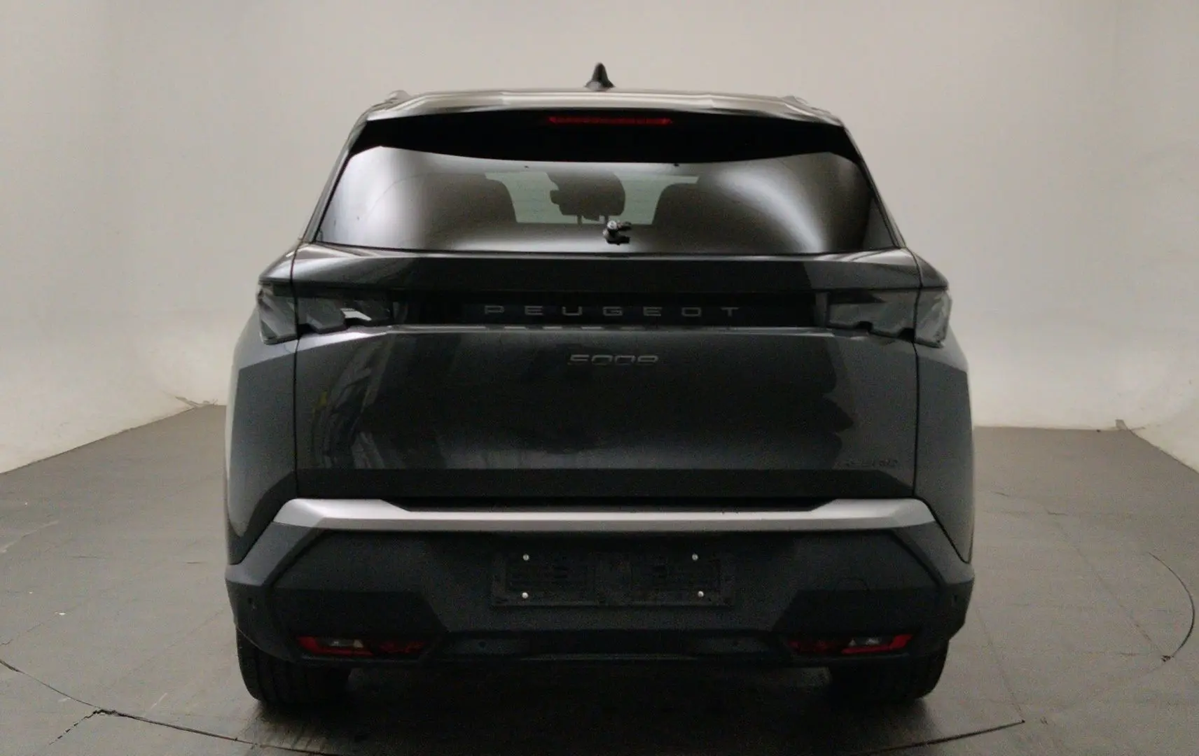 Vue arrière d’un Peugeot 5008 III Hybrid 145 gris titane avec feux arrière noirs et lunette teintée.