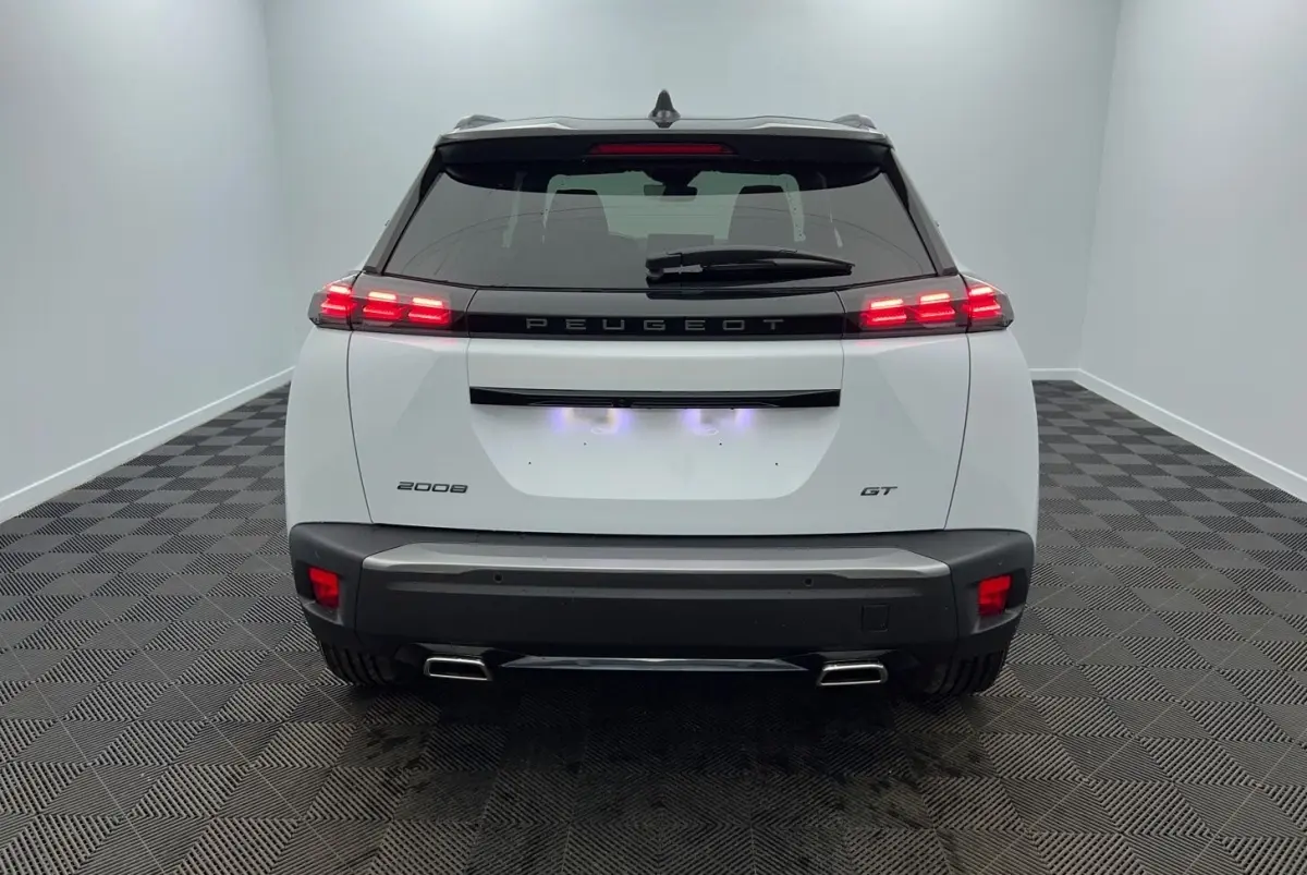 Vue arrière d'un Peugeot 2008 blanc avec feux LED allumés et double sortie d'échappement chromée.