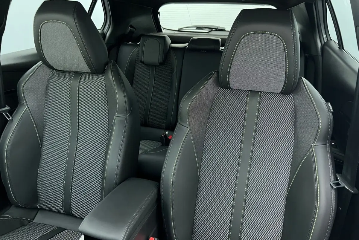 Vue intérieure des sièges avant et arrière en tissu noir et gris du Peugeot 2008 Hybrid 145 e-DCS6 GT.