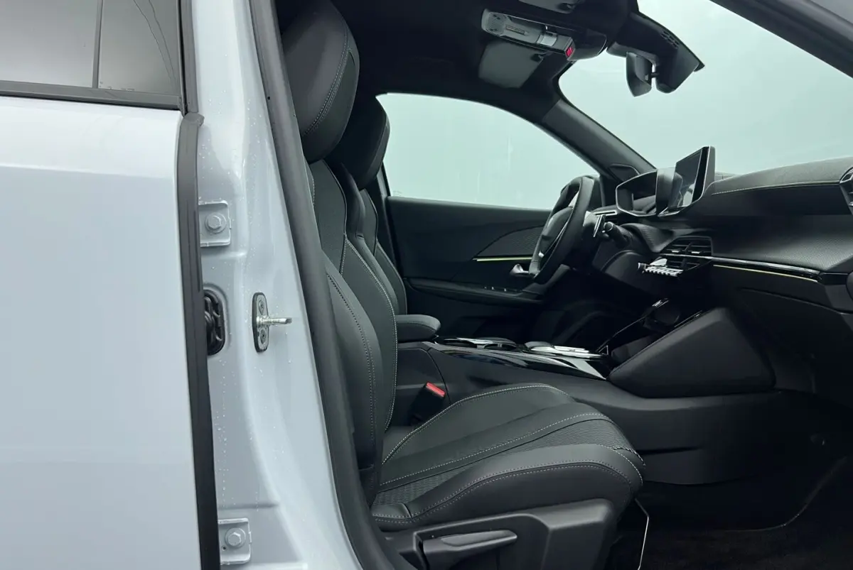 Intérieur côté conducteur du Peugeot 2008 Hybrid blanc 2025, sièges noirs et tableau de bord moderne avec écran tactile.