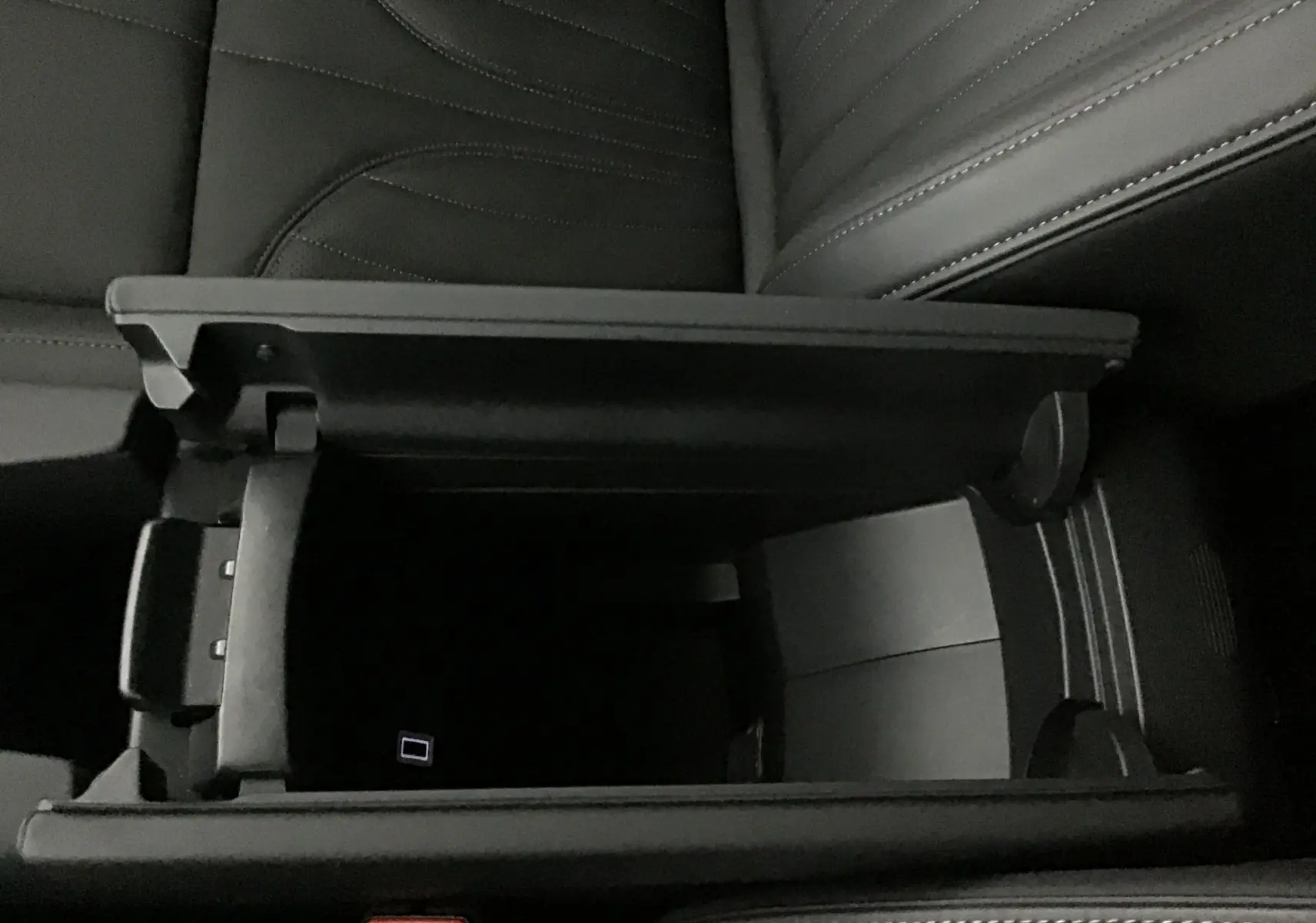 Gros plan sur l'accoudoir central ouvert en cuir noir du DS4 2022, révélant un espace de rangement intérieur.