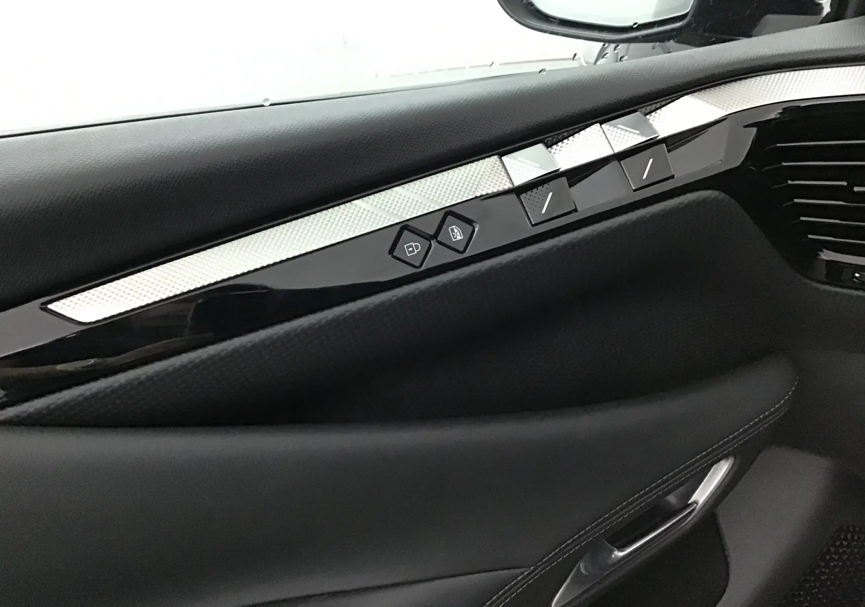 Détail de la porte côté gauche du DS4 2022 noir, mettant en valeur les commandes de vitres et la finition intérieure élégante.