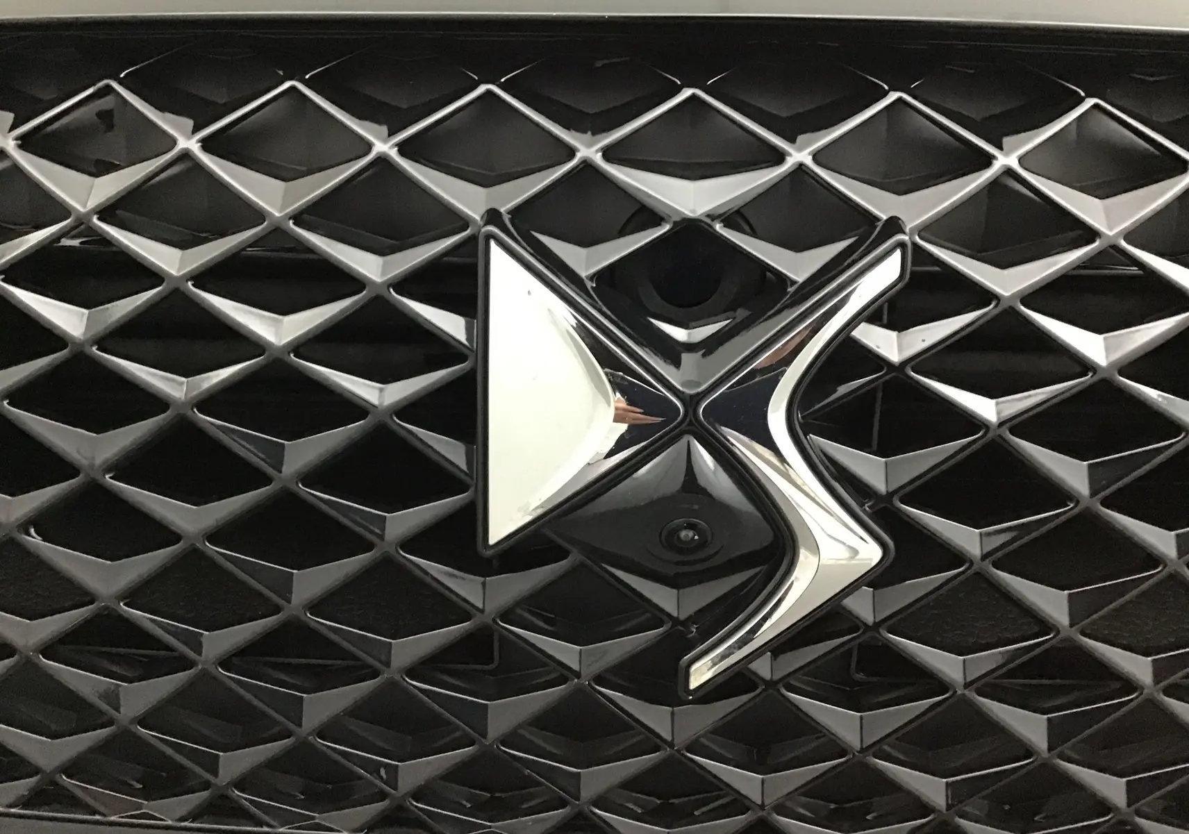 Gros plan sur la calandre noire du DS4 2022 avec le logo DS chromé en relief au centre.