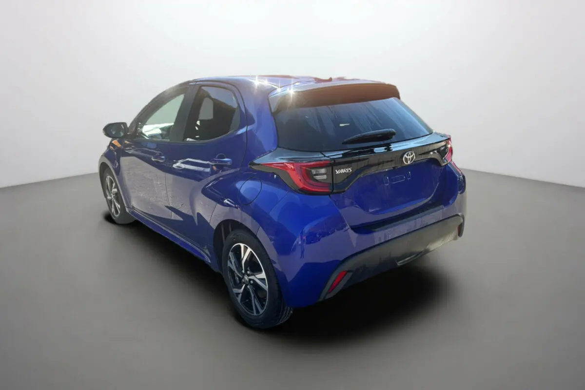 Toyota Yaris 1.5 Hybrid 2025 bleu genièvre vue 3/4 arrière droit avec feux arrière distinctifs noirs.