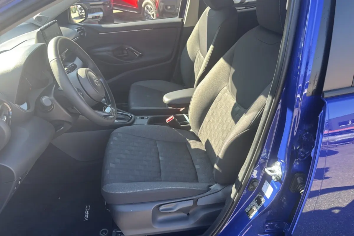 Vue intérieure côté conducteur de la Toyota Yaris 1.5 Hybrid 116 BVA Design 2025 en bleu genievre, sièges tissu gris.