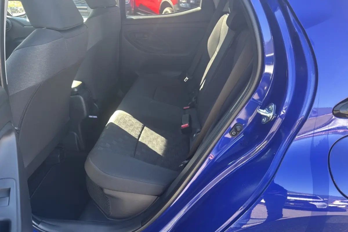 Vue intérieure sur la banquette arrière côté gauche d'une Toyota Yaris 1.5 Hybrid 2025 bleu genievre avec sièges tissu noir.