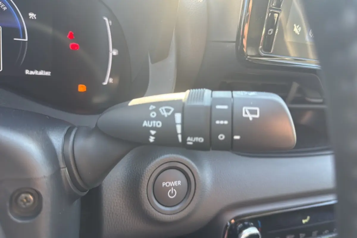 Détail intérieur du Toyota Yaris 2025 montrant la commande d'essuie-glace et le bouton Power sur tableau de bord noir.