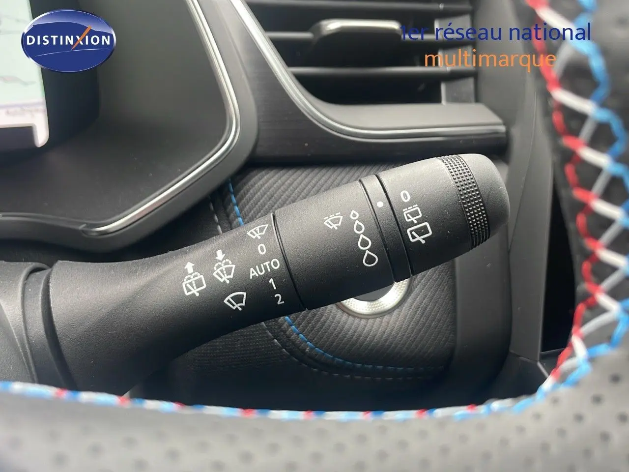 Gros plan sur la commande d'essuie-glace du Renault Captur E-Tech blanc nacré, avec surpiqûres bleues visibles.