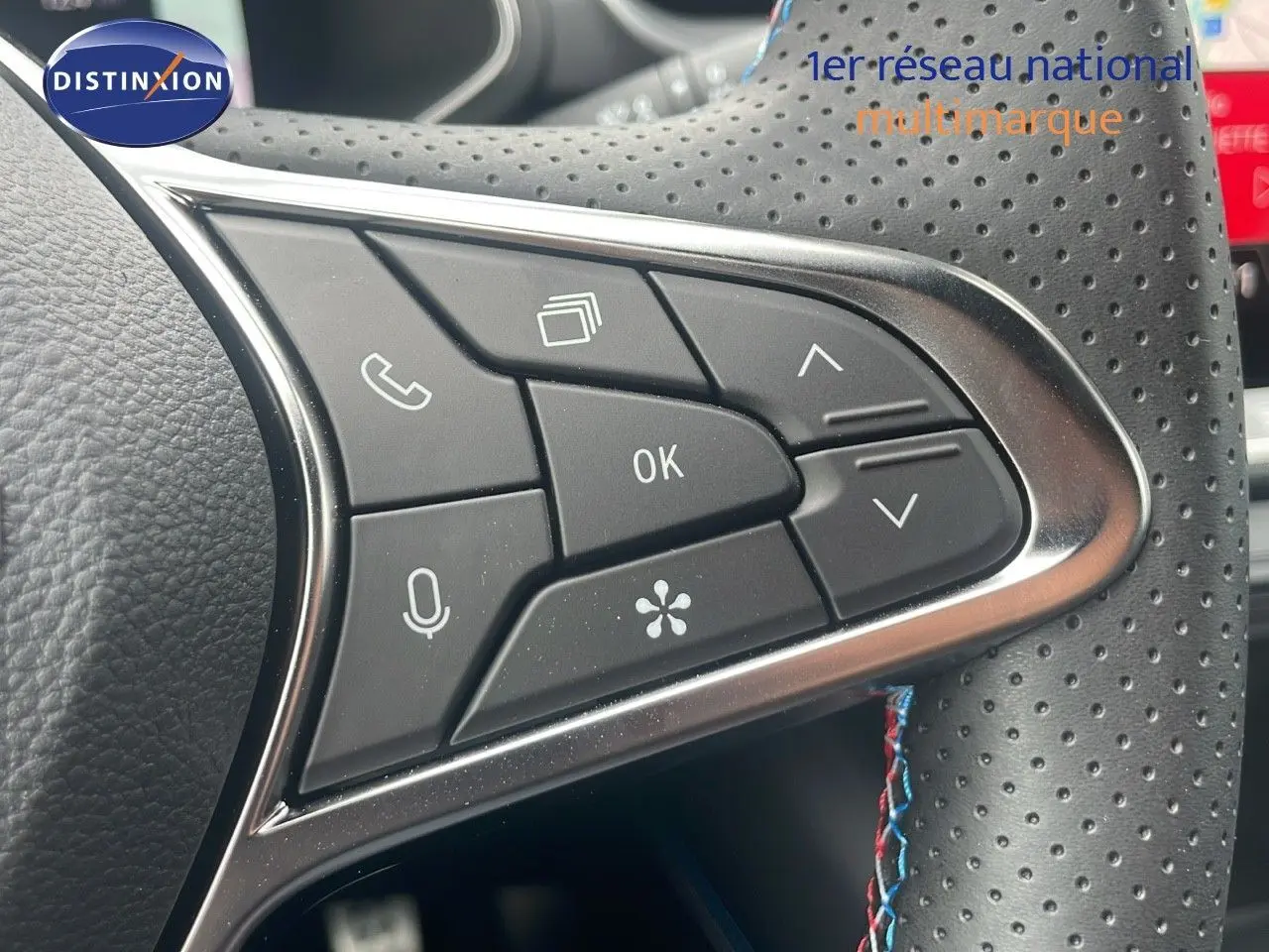 Gros plan sur les commandes multifonctions du volant en cuir perforé du Renault Captur E-Tech blanc nacré toit noir.