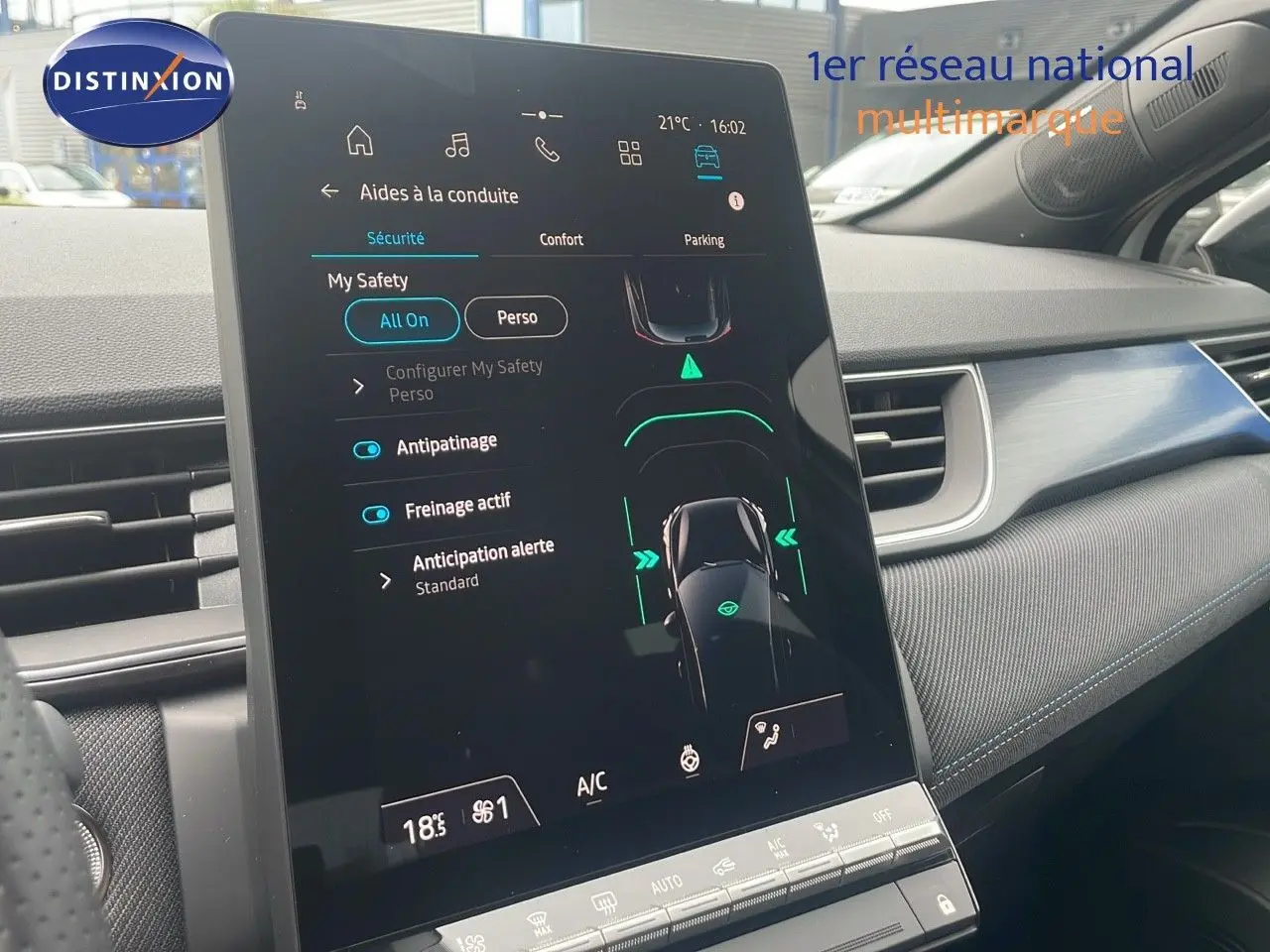 Écran tactile central affichant les aides à la conduite dans l’habitacle d’un Renault Captur blanc nacré toit noir, vue de côté droit.