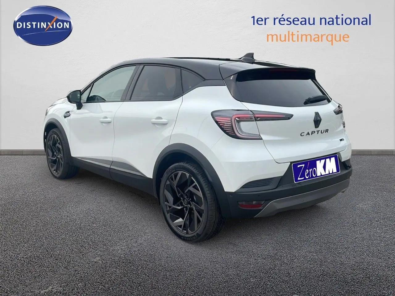 Renault Captur E-Tech hybride blanc nacré avec toit noir, vu de l'arrière côté droit, jantes noires distinctives.