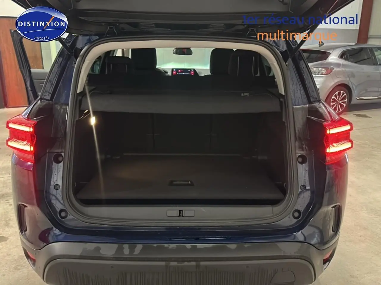 Vue arrière du Citroën C5 Aircross bleu eclipse 2025 avec coffre ouvert et feux arrière allumés.