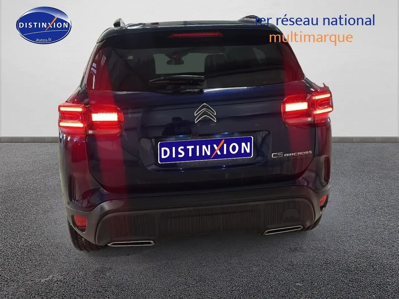 Vue arrière du Citroën C5 Aircross bleu eclipse avec feux arrière allumés et double sortie d'échappement visible.