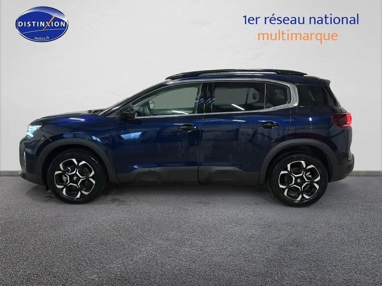 Vue de profil côté gauche d'un Citroën C5 Aircross bleu eclipse avec jantes alliage et barres de toit noires.