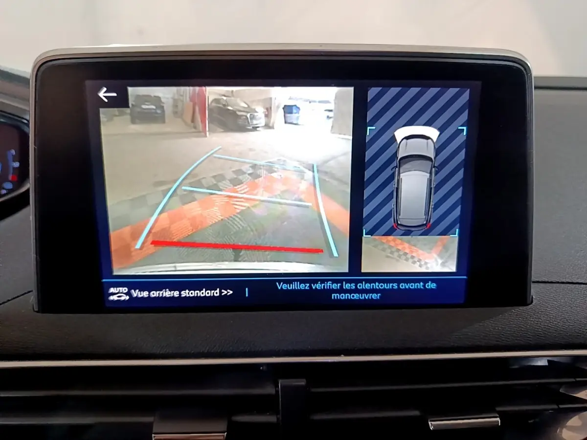 Écran tactile intérieur montrant la caméra de recul et l’aide au stationnement du Peugeot 3008 blanc hybride.