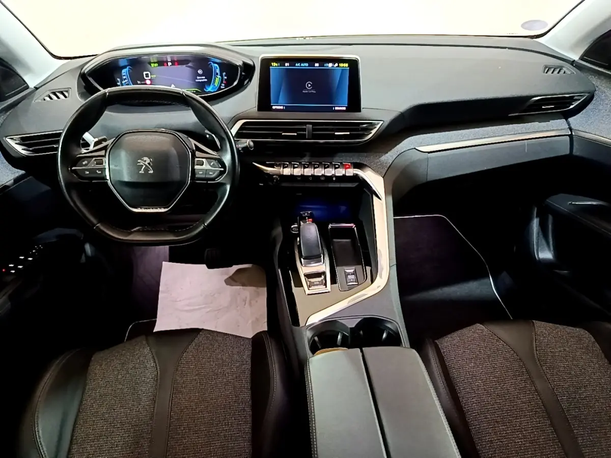 Vue intérieure avant du Peugeot 3008 hybride blanc, tableau de bord numérique et console centrale avec levier de vitesses.