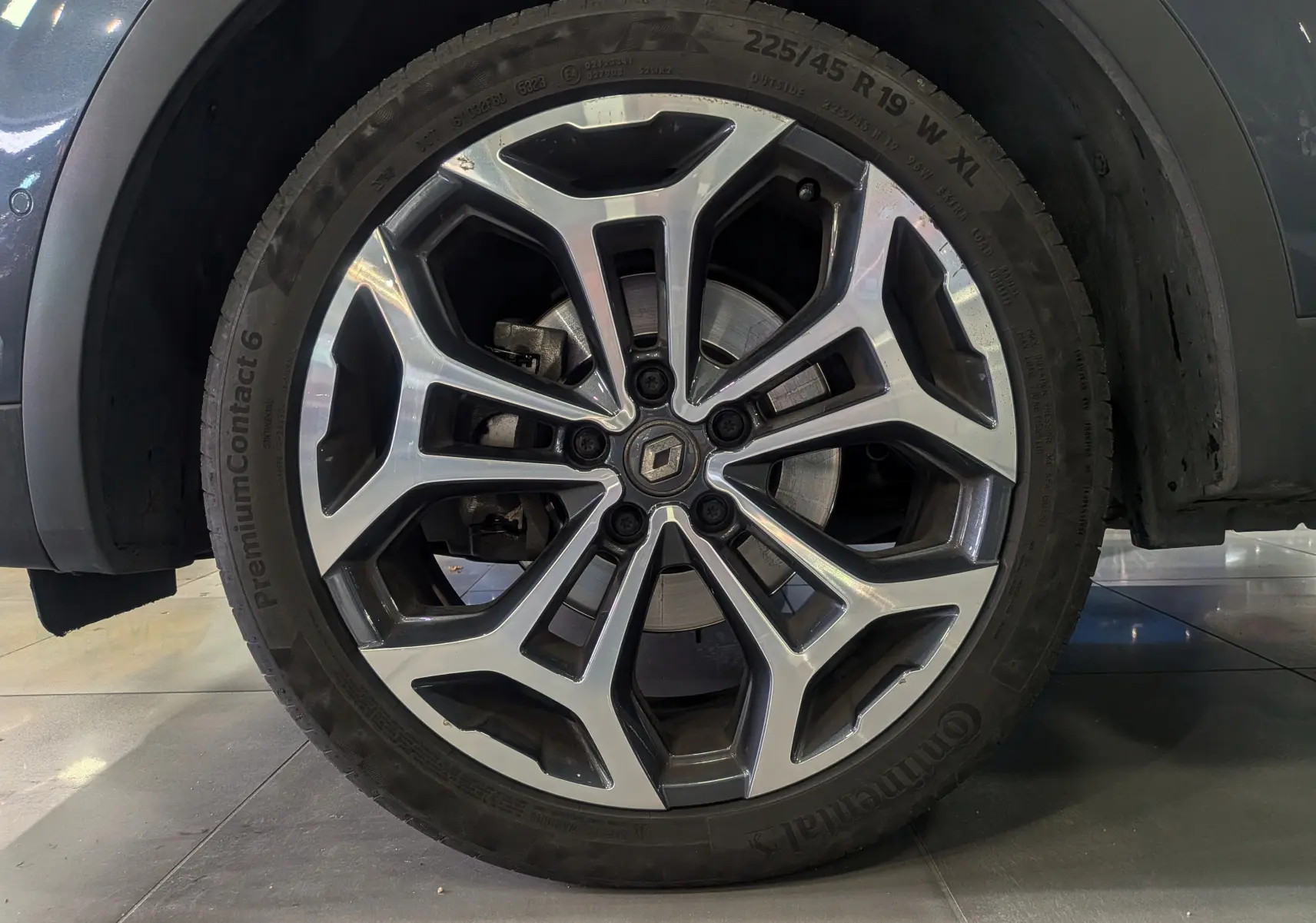 Gros plan sur la roue avant droite du Renault Kadjar gris titanium, mettant en valeur la jante alliage bicolore au design moderne.