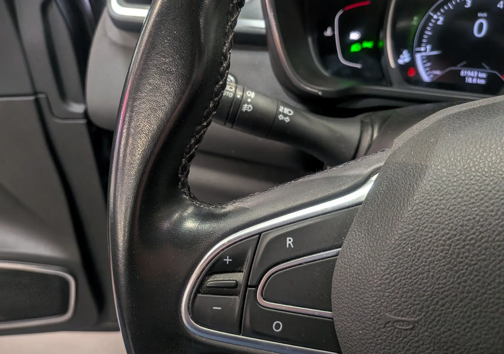 Gros plan sur le volant en cuir noir du Renault Kadjar TCe 140 CH Intens, avec commandes intégrées et tableau de bord partiellement visible.
