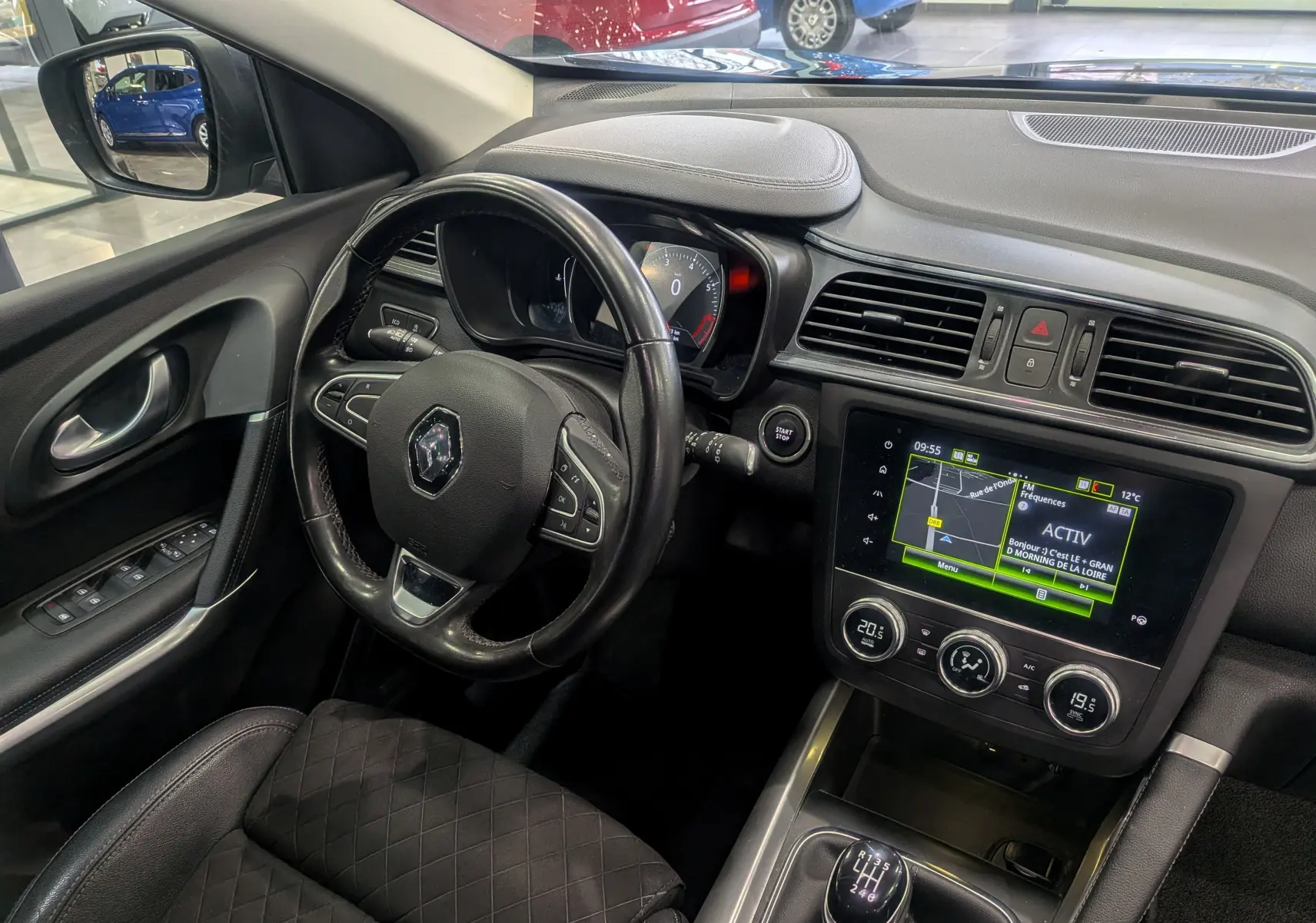 Vue intérieure côté conducteur du Renault Kadjar TCe 140 Intens 2019, volant cuir noir et écran tactile central allumé.