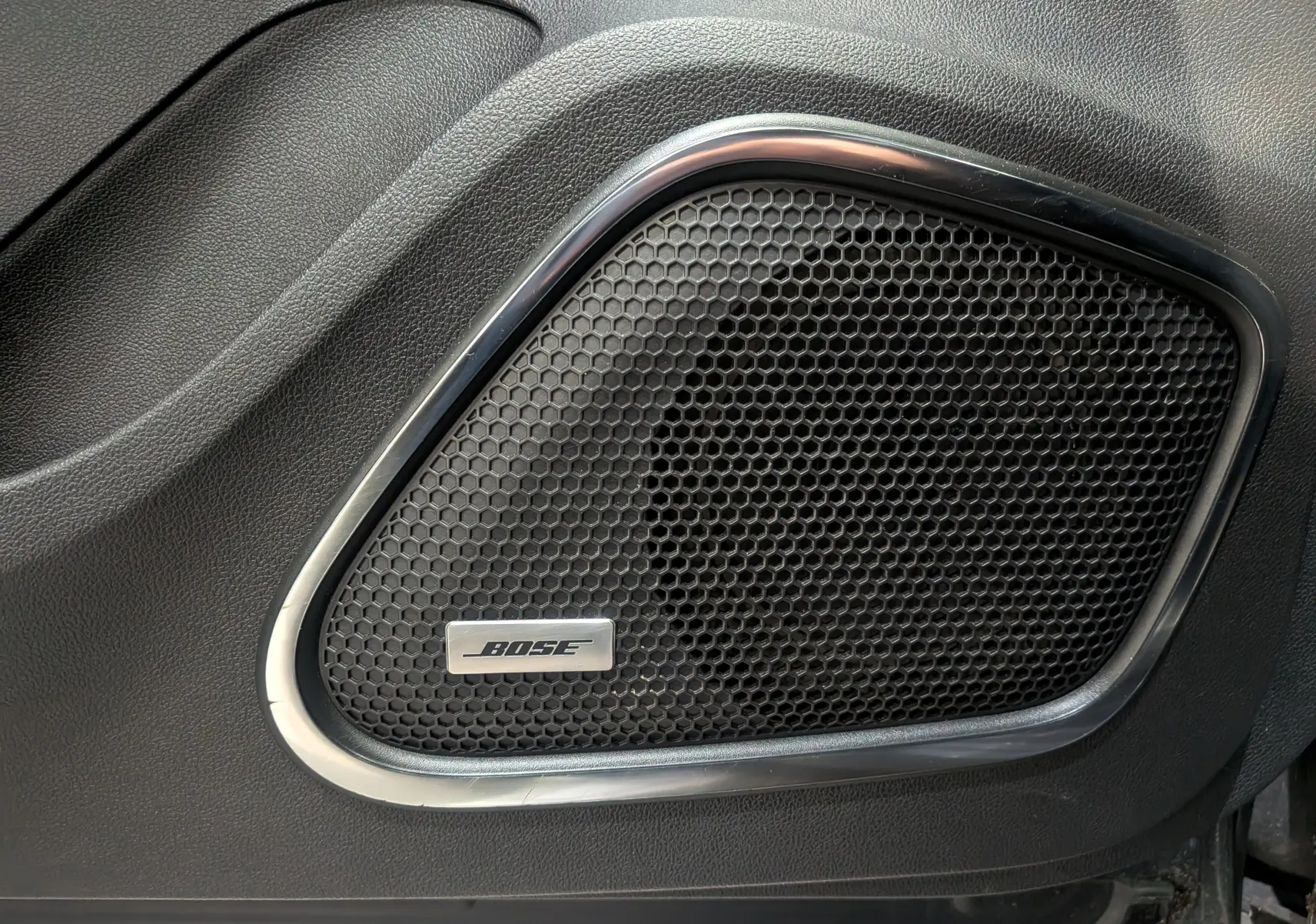 Gros plan sur l'enceinte Bose intégrée dans la porte intérieure noire du Renault Kadjar TCe 140 Gris Titanium.