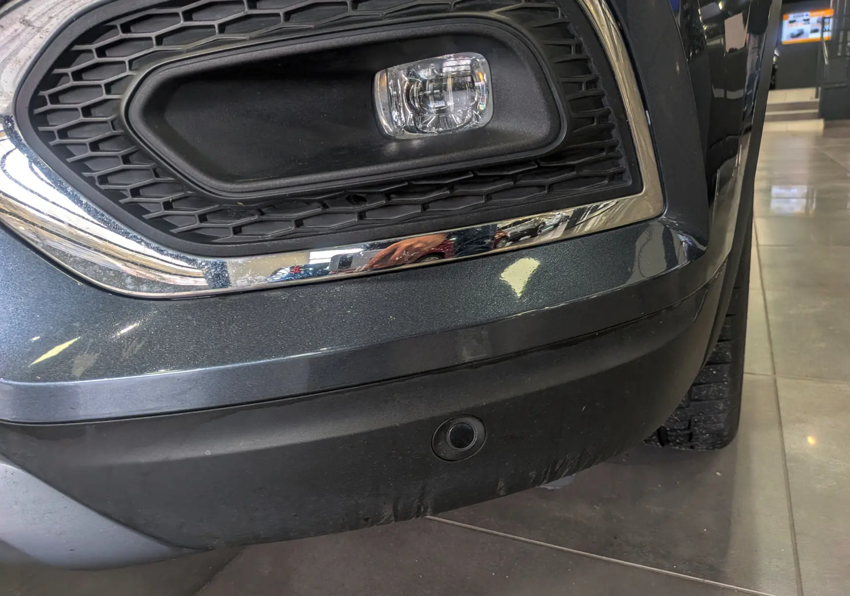 Gros plan sur le pare-chocs avant droit gris titanium du Renault Kadjar TCe 140 CH Intens avec antibrouillard et radar de recul.