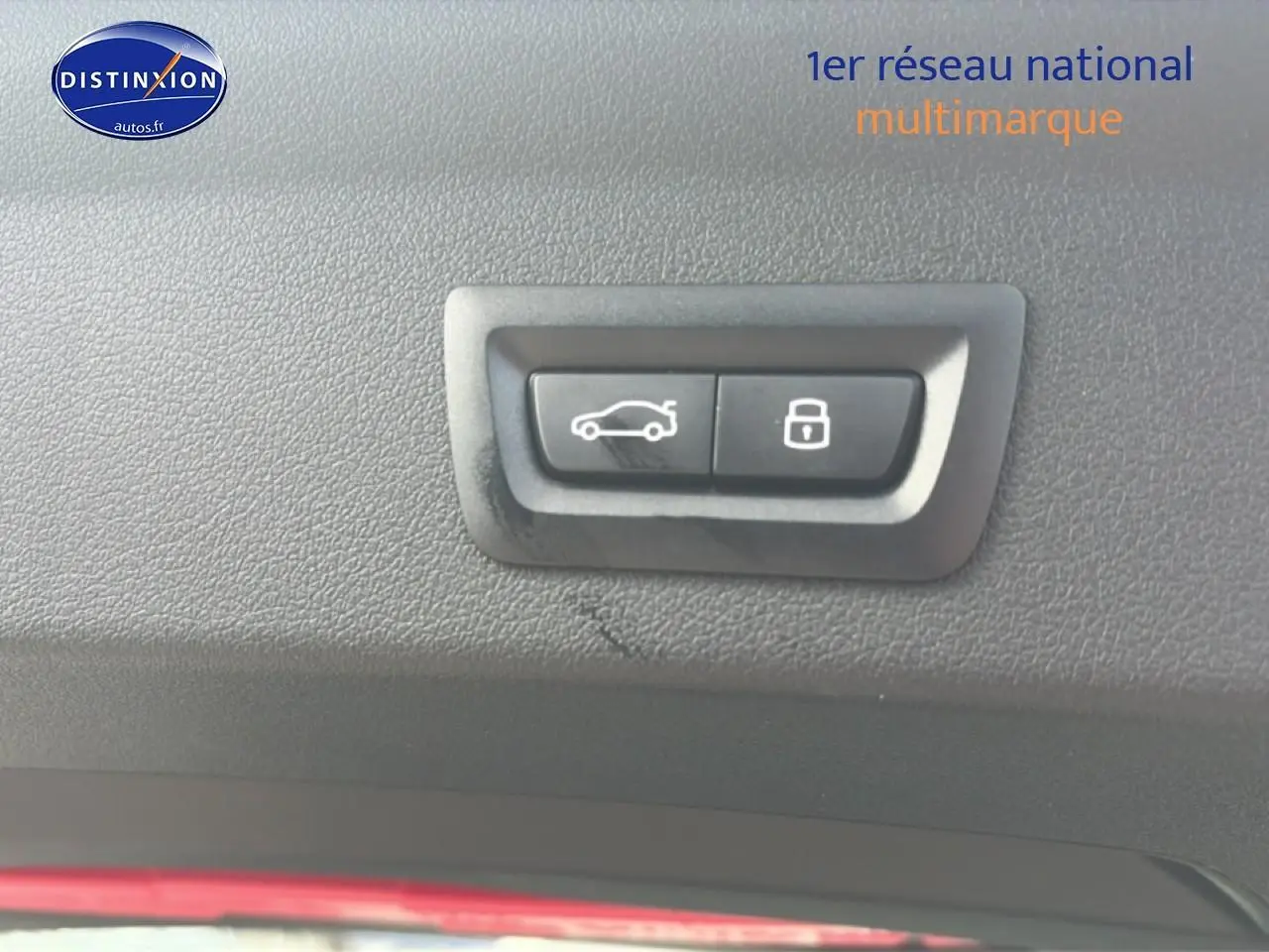 Boutons d'ouverture de coffre et de verrouillage intégrés dans le panneau intérieur noir d'une BMW Série 1 blanche.