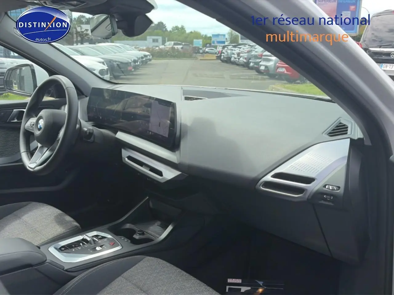 Vue intérieure côté passager de la BMW Série 1 blanche, avec tableau de bord moderne et écran tactile large.