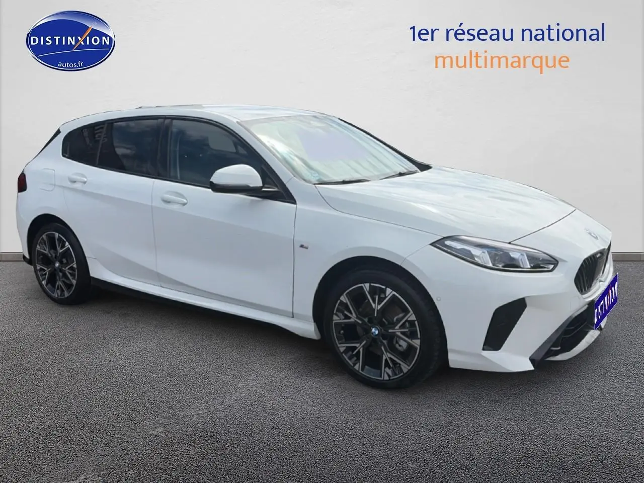 BMW Série 1 blanche vue en 3/4 avant droit, avec jantes alliage noires et toit noir contrasté.