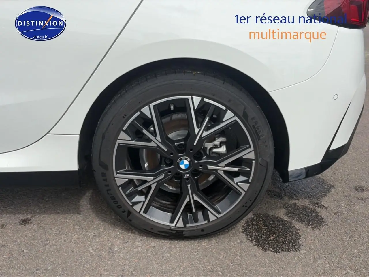 Gros plan sur la roue arrière droite d'une BMW Série 1 blanche avec jante alu noire et grise design M Sport.