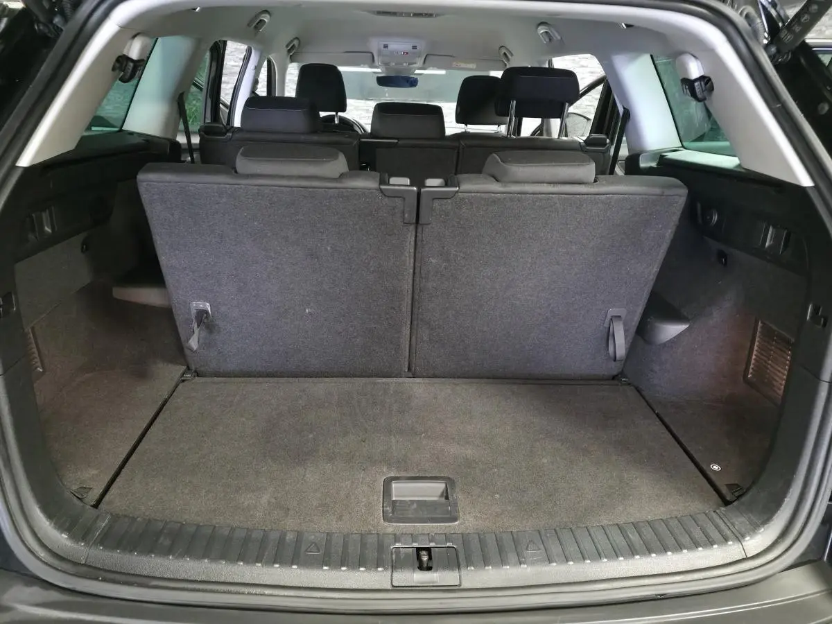 Coffre ouvert vu de l'arrière d'un Skoda Kodiaq noir 7 places avec banquette arrière relevée et intérieur tissu gris.
