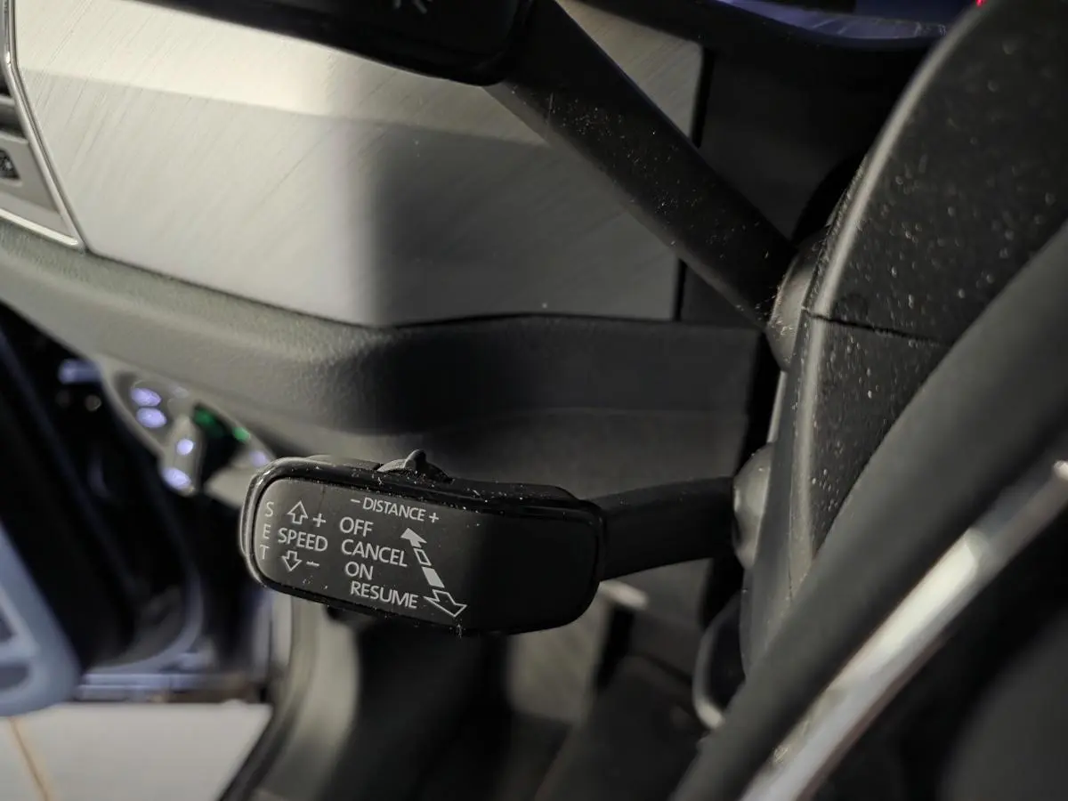 Gros plan sur la commande du régulateur de vitesse adaptatif à gauche du volant dans un intérieur noir du Skoda Kodiaq 2023.