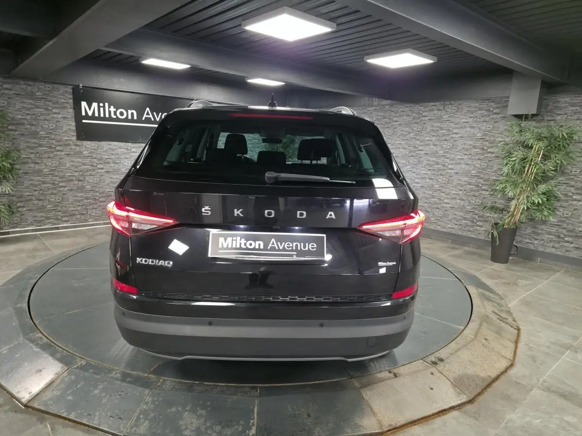 Vue arrière d'un Skoda Kodiaq noir 2023 avec feux arrière LED allumés dans un showroom intérieur.
