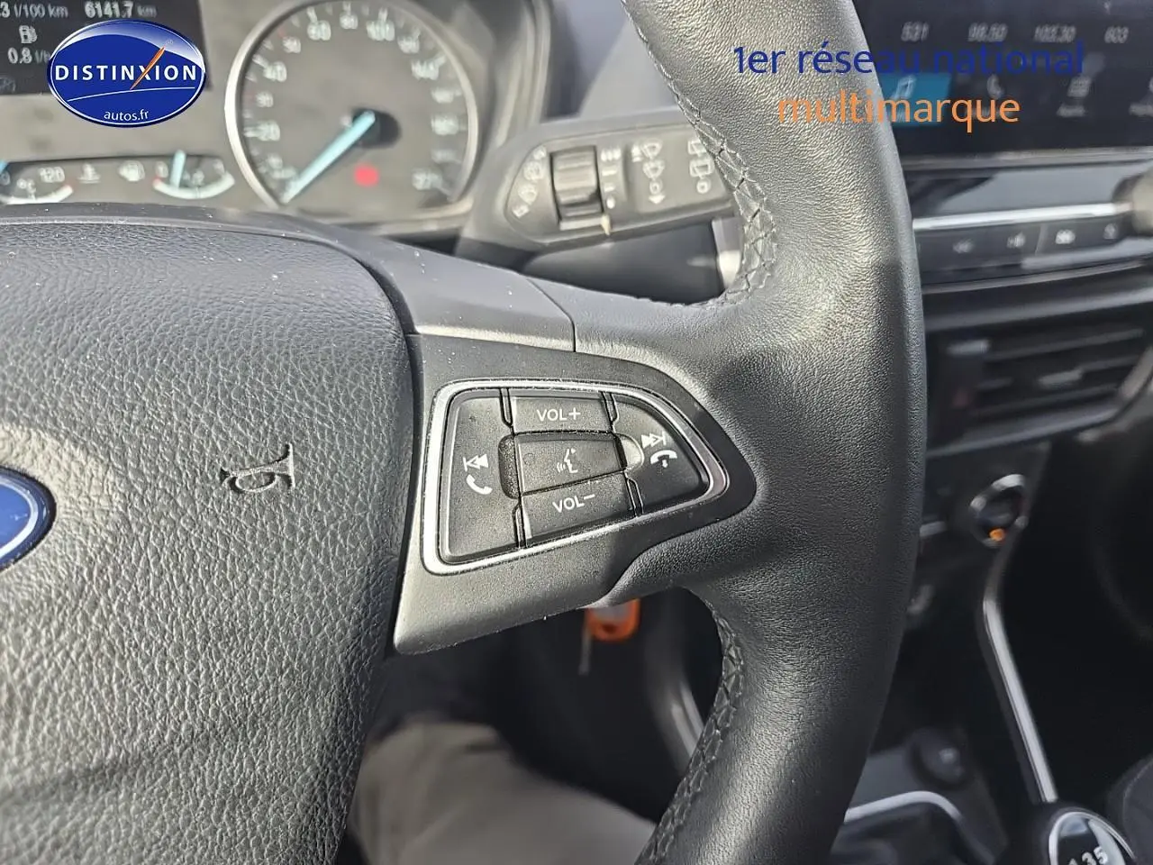 Gros plan sur le volant cuir côté gauche du Ford EcoSport gris, avec commandes vocales et tableau de bord en arrière-plan.