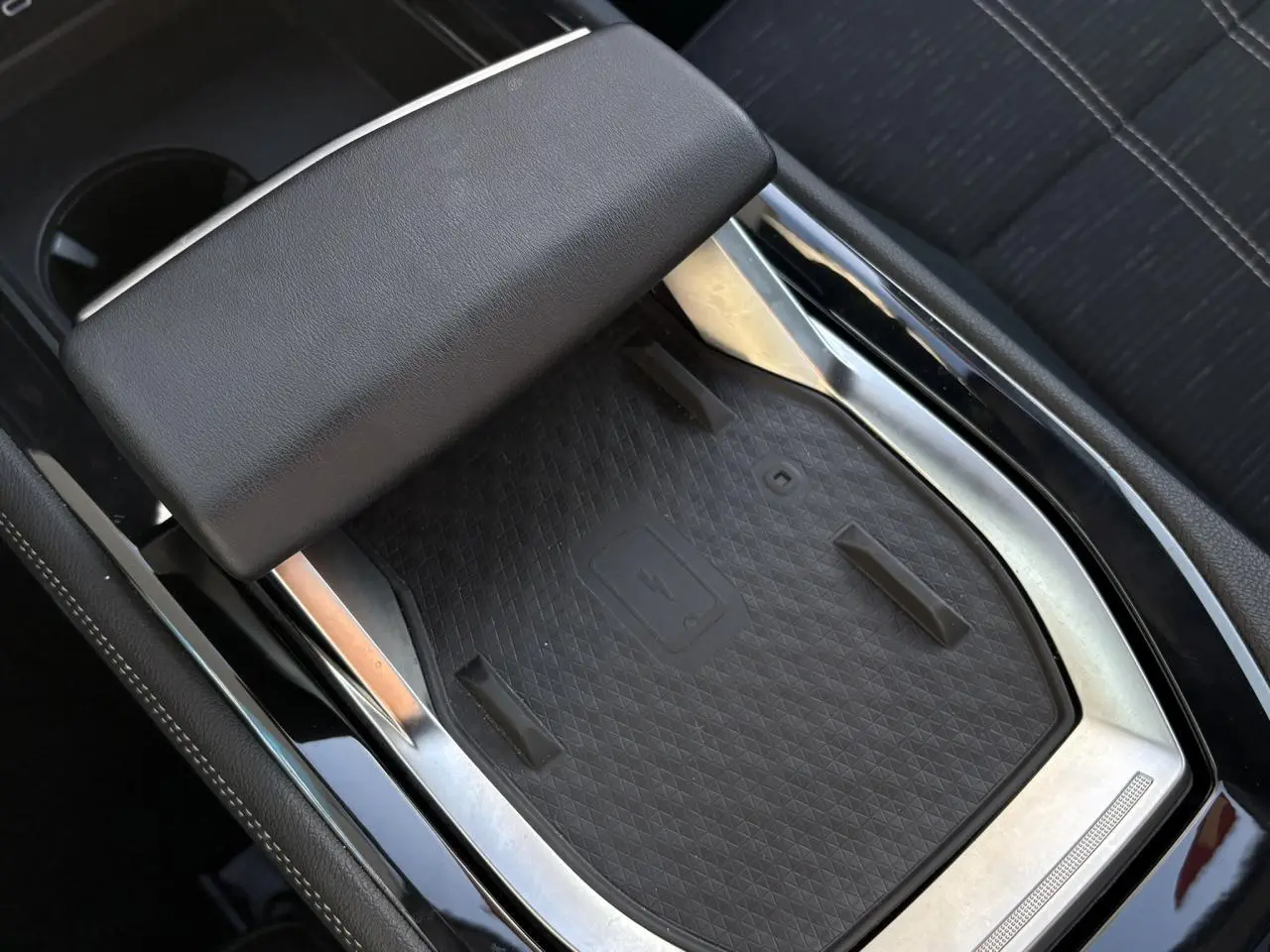 Gros plan sur le chargeur sans fil et accoudoir central noir dans l’habitacle du Renault Austral E-Tech blanc nacré.