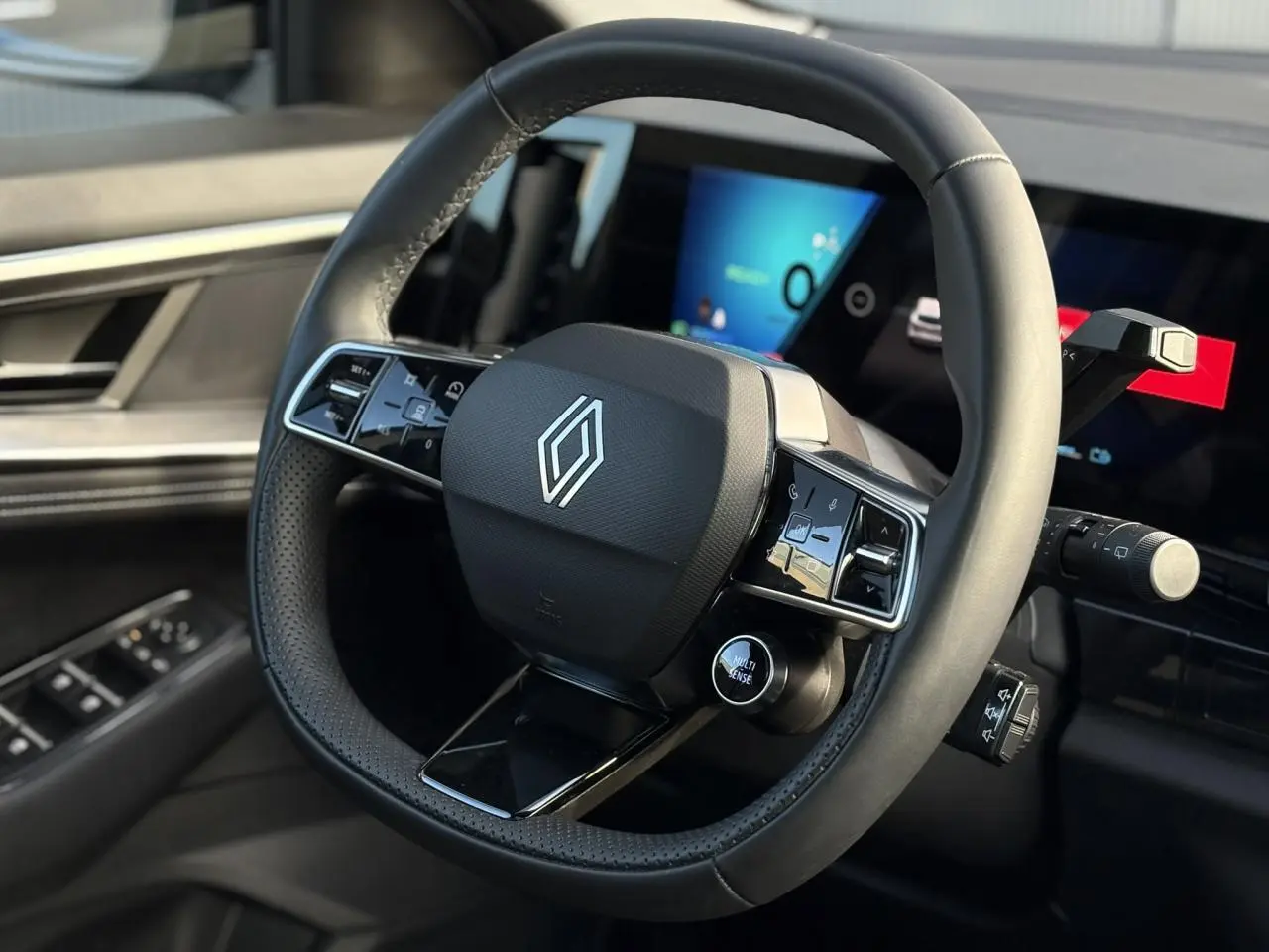 Gros plan sur le volant noir texturé du Renault Austral 2025 avec commandes intégrées et tableau de bord numérique en arrière-plan.