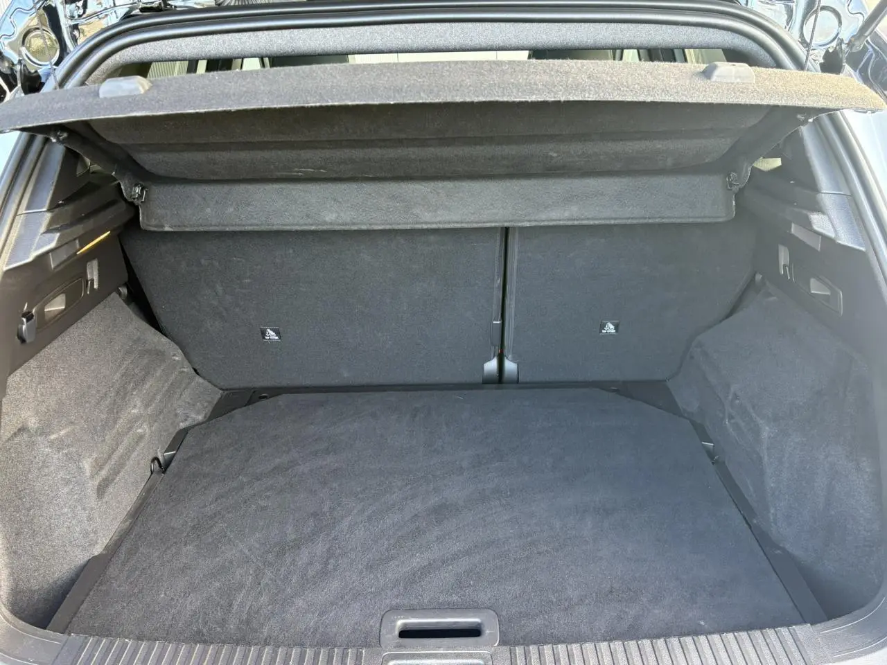 Vue intérieure du coffre ouvert du Renault Austral E-Tech, montrant un espace de rangement propre et tapissé de tissu noir.
