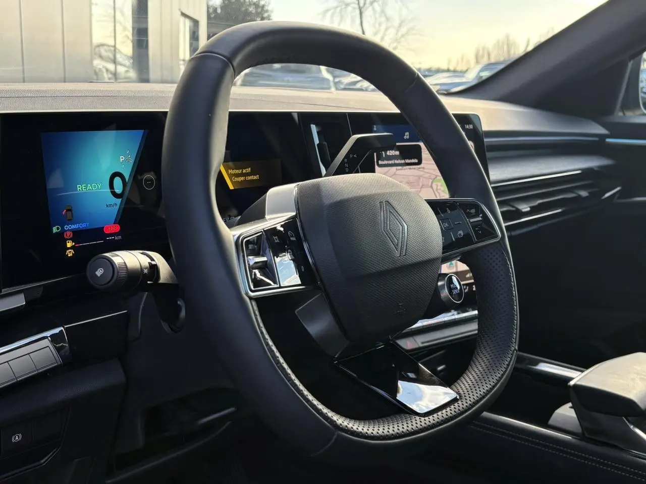 Vue intérieure du volant Renault Austral E-Tech avec tableau de bord numérique et écran central tactile, ambiance noire moderne.
