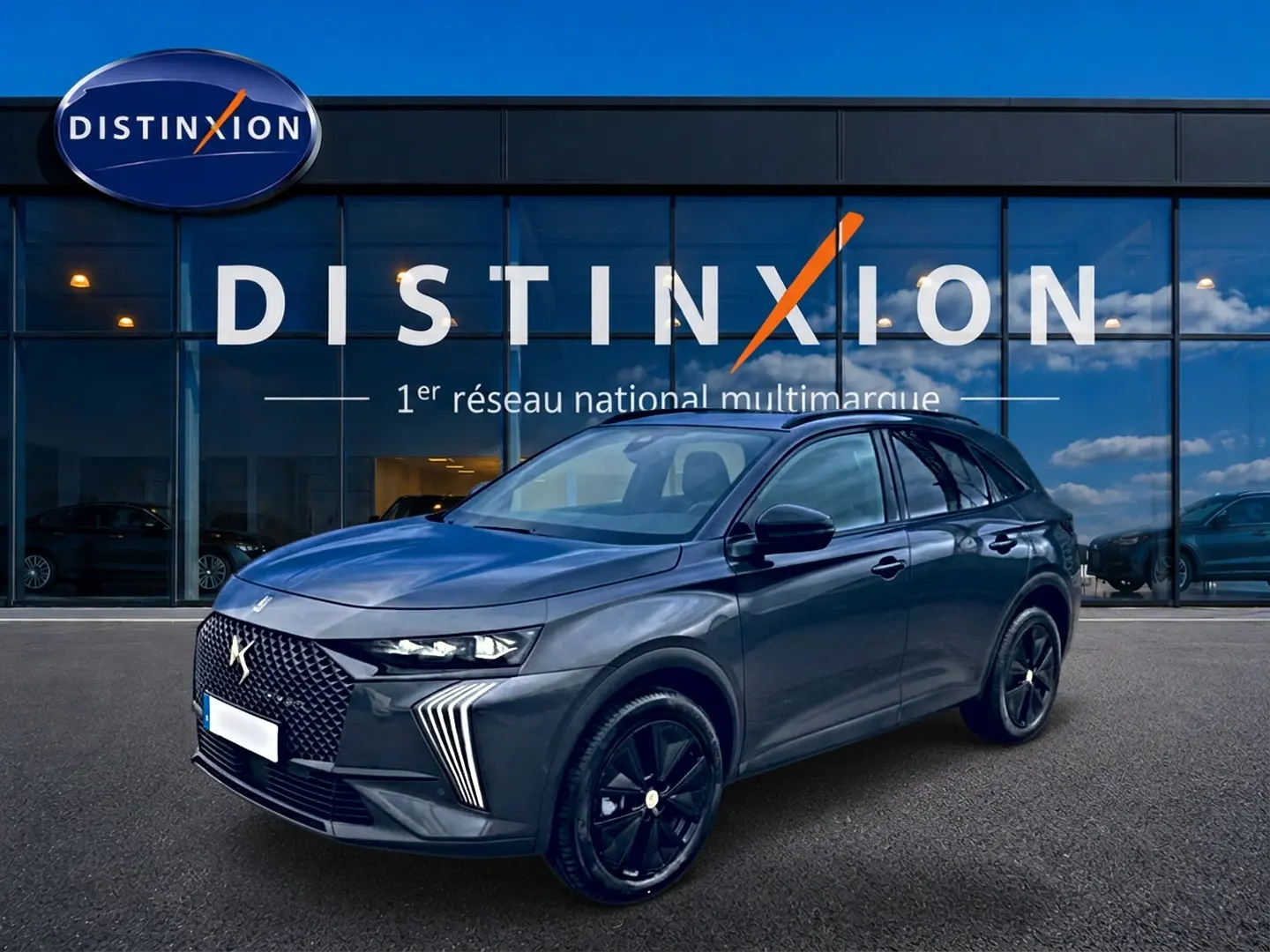 DS7 1.5 BlueHDi 130 gris titane en 3/4 avant droit, avec calandre distinctive et jantes noires brillantes.