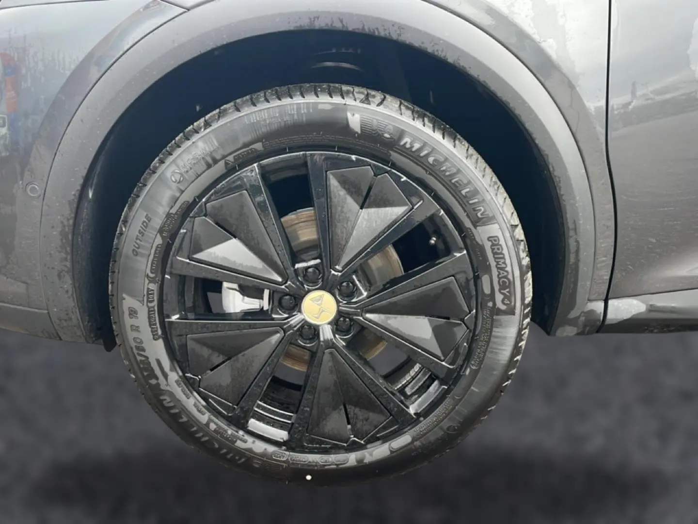 Gros plan sur la roue avant gauche du DS7 gris titane avec jante alu noire au design géométrique.