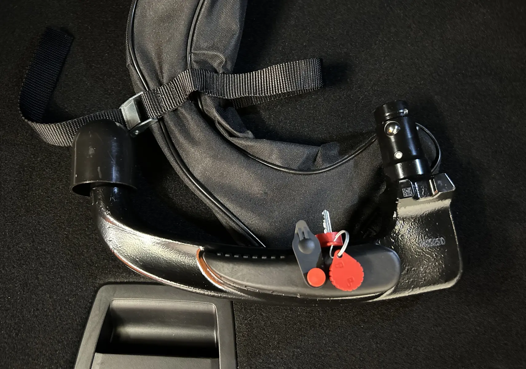 Attelage amovible noir avec clé et housse de protection sur fond de moquette noire, accessoire pour Peugeot 3008 bleu.