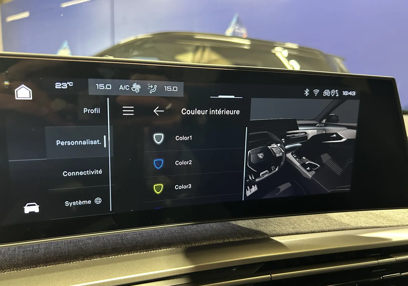 Écran tactile intérieur du Peugeot 3008 III Hybrid 145, affichant les options de personnalisation de couleur, avec reflet d’un véhicule bleu en arrière-plan.
